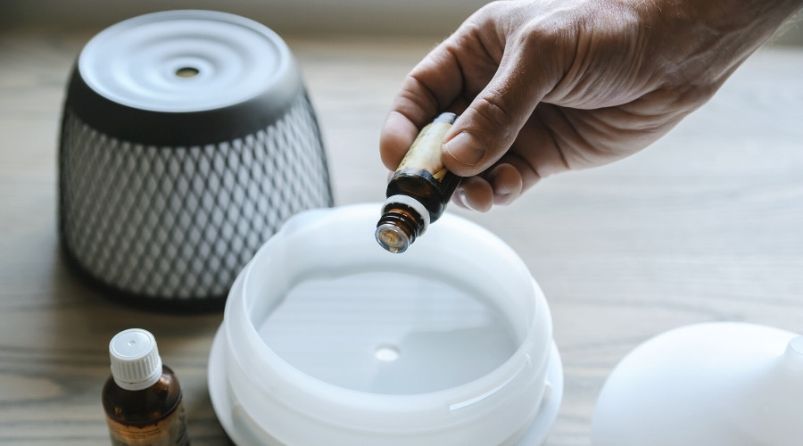 person placing drops of essential oils into a diffuser